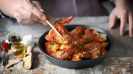 Selective focus. Male hand with chopsticks keeps spicy chicken wings. Chicken wings in Chinese style.