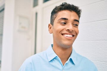 Young latin man smiling happy walking at the city.