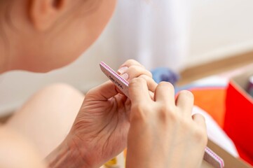 Woman's hands filing her nails with a red blouse.