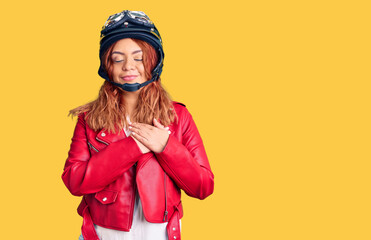 Young latin woman wearing leather jacket holding motorcycle helmet smiling with hands on chest with closed eyes and grateful gesture on face. health concept.