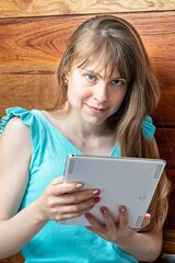 Light-eyed blonde woman with white helmet
of engineer reading a tablet