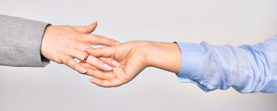 Hand of caucasian young woman putting golden marriage ring to other person over isolated white background