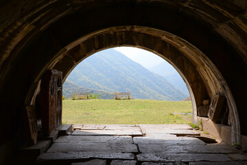 View through an archway in Haghpat Monastery Complex in Armenia showing grass and mountain. Also know as Haghpatavank. Arch built in a monolith.