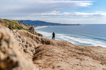 Man with panoramic view of ocean with distant pier and parachuter in San Diego