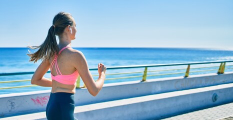 Young blonde sportswoman running at the promenade.