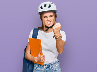 Beautiful young blonde woman wearing backpack and bike helmet annoyed and frustrated shouting with anger, yelling crazy with anger and hand raised