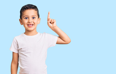 Little cute boy kid wearing casual white tshirt pointing finger up with successful idea. exited and...