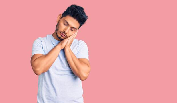 Handsome latin american young man wearing casual clothes sleeping tired dreaming and posing with hands together while smiling with closed eyes.