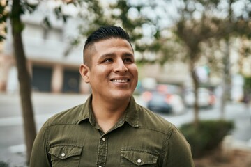 Young latin man smiling happy standing at the city.