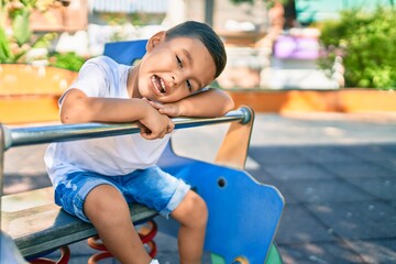 Fototapeta na wymiar Adorable hispanic boy smiling happy playing at the park.