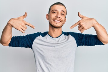 Hispanic young man wearing casual clothes looking confident with smile on face, pointing oneself...