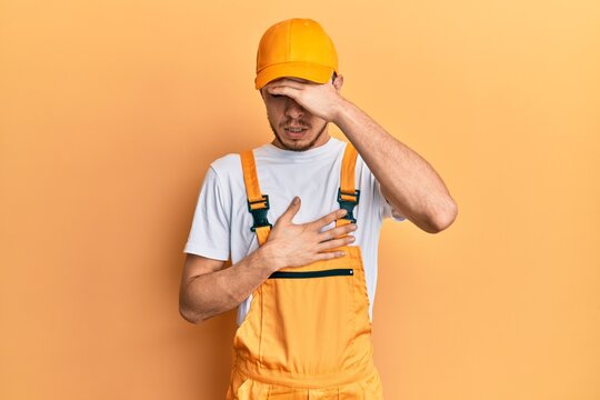 Hispanic young man wearing handyman uniform touching forehead for illness and fever, flu and cold, virus sick