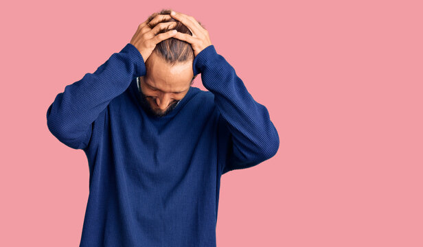 Handsome blond man with beard wearing casual sweater suffering from headache desperate and stressed because pain and migraine. hands on head.