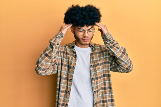 Young african american man with afro hair wearing casual clothes with hand on head, headache because stress. suffering migraine.