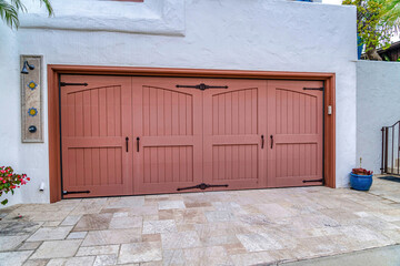 Two car garage with hinged wood doors against white wall in San Diego California
