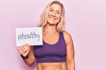 Middle age caucasian blonde woman wearing sportswear holding healthy banner looking positive and happy standing and smiling with a confident smile showing teeth