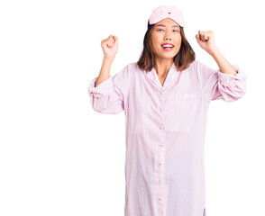 Fototapeta na wymiar Young beautiful chinese girl wearing sleep mask and pajama celebrating surprised and amazed for success with arms raised and open eyes. winner concept.