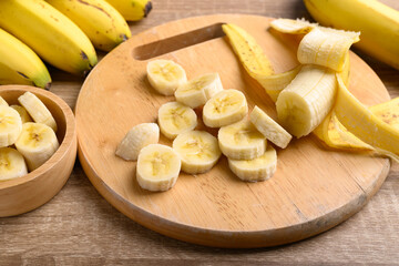 Sliced ripe banana fruit on wooden cutting board preparing for cooking