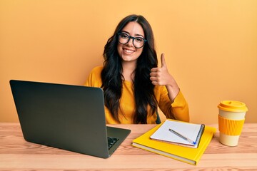 Beautiful brunette young woman working at the office wearing glasses smiling happy and positive,...