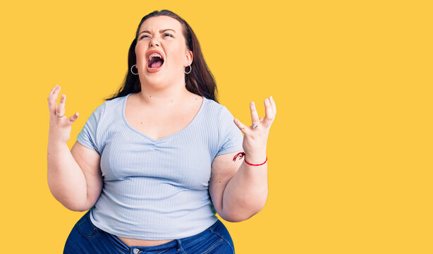 Young plus size woman wearing casual clothes crazy and mad shouting and yelling with aggressive expression and arms raised. frustration concept.