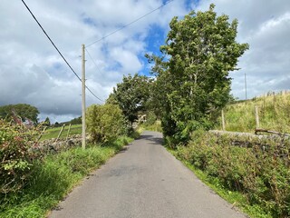 Looking along, Carr Lane, with dry stone walls, old trees, with heavy clouds above in, Micklethwaite, Bradford, UK