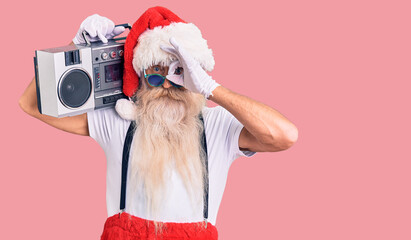 Old senior man with grey hair and long beard wearing santa claus costume and boombox smiling happy...