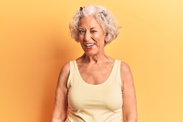 Senior grey-haired woman wearing casual clothes winking looking at the camera with sexy expression, cheerful and happy face.