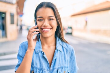 Young latin girl smiling happy talking on the smartphone at the city.