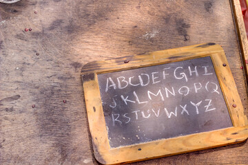 Home Schooling. Hand held chalkboard with alphabet written in chalk. Horizontal orientation with copy space.
