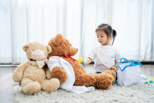 A happy asian girl smiling and lying on the floor with playing teddy bear