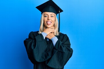 Beautiful blonde woman wearing graduation cap and ceremony robe shouting and suffocate because painful strangle. health problem. asphyxiate and suicide concept.