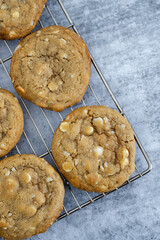 Macadamia white chocolate chip cookies close up on a cooling rack and concrete background