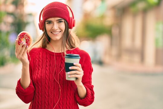 Young hispanic woman having breakfast using headphones at the city.