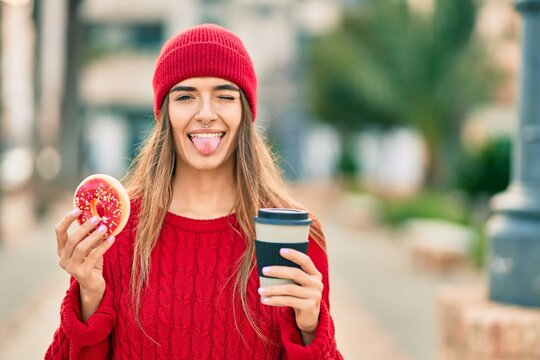 Young hispanic woman wearing wool cap having breakfast at the city.