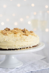Carrot cake close up on a cake stand with lights and champagne glasses in the background