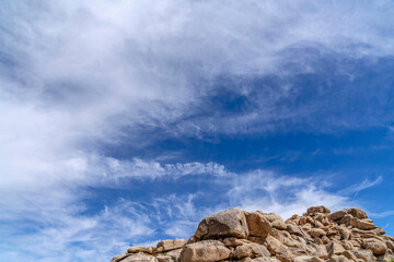 Peak of rock mountain against blue sky and clouds in Joshua Tree California