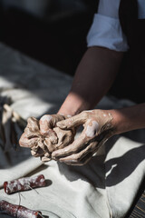 Obraz na płótnie Canvas Woman's hands wet and dirty after working with clay in a pottery studio