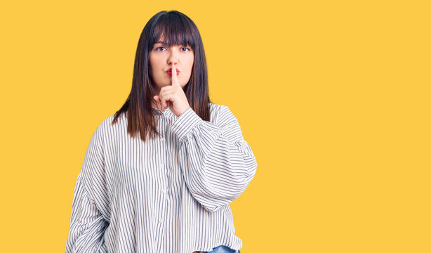 Young plus size woman wearing casual clothes asking to be quiet with finger on lips. silence and secret concept.