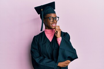 Young african american girl wearing graduation cap and ceremony robe looking confident at the...
