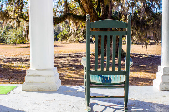 Single empty rocking chair on the front porch of an antebellum style house in the southern United States.