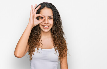 Teenager hispanic girl wearing casual clothes doing ok gesture with hand smiling, eye looking through fingers with happy face.