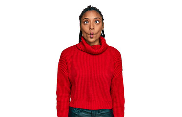 African american woman wearing casual winter sweater making fish face with lips, crazy and comical gesture. funny expression.