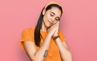 Fototapeta premium Young hispanic woman wearing casual clothes sleeping tired dreaming and posing with hands together while smiling with closed eyes.