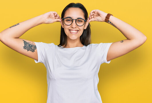 Young hispanic woman wearing casual white t shirt smiling pulling ears with fingers, funny gesture. audition problem