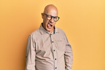 Middle age bald man wearing casual clothes and glasses winking looking at the camera with sexy...