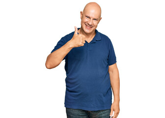 Middle age bald man wearing casual clothes doing happy thumbs up gesture with hand. approving expression looking at the camera showing success.