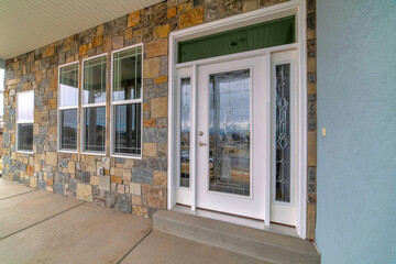 Beautiful glass front door with sidelights and transom window at the home facade