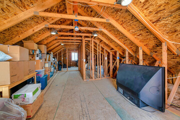 Interior of the attic of house with boxes and old appliances under gable roof