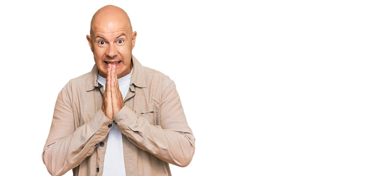 Middle age bald man wearing casual clothes praying with hands together asking for forgiveness smiling confident.