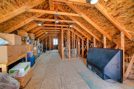Interior of the attic of house with boxes and old appliances under gable roof